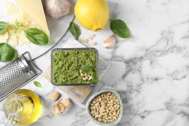 Flat lay composition with delicious pesto sauce and ingredients on white marble table. Space for text