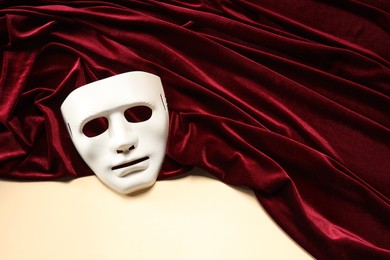 Theater arts. White mask and red fabric on beige background, above view