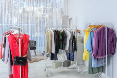 Wardrobe racks with different stylish clothes in light room