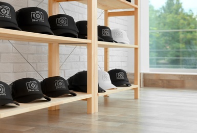 Photo of Many caps with logo on wooden rack in shop