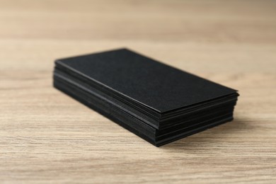Photo of Blank black business cards on wooden table, closeup. Mockup for design