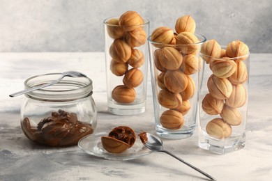 Tasty walnut shaped cookies served in glasses for welcoming guests on light grey table. Homemade pastry with caramelized condensed milk filling