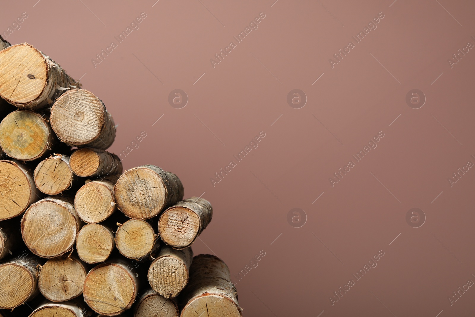 Photo of Cut firewood on pink background. Space for text