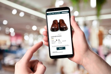 Image of Man visiting shop to take ordered shoes indoors, closeup. Online store website on device screen