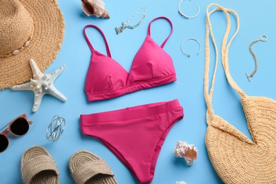 Photo of Beautiful pink bikini and beach accessories on light blue background, flat lay