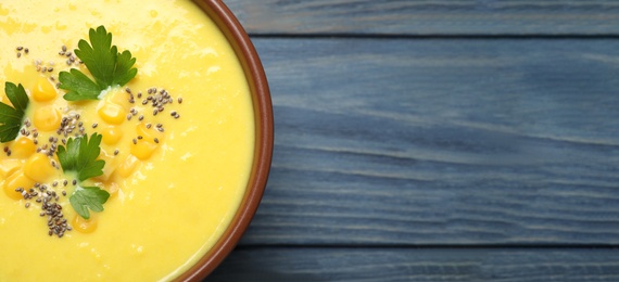 Delicious creamy corn soup on blue wooden table, top view