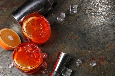 Photo of Aperol spritz cocktail, ice cubes and orange slices in glasses on grey textured table, above view. Space for text