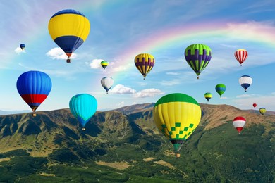 Image of Bright hot air balloons flying in sky with rainbow over mountain