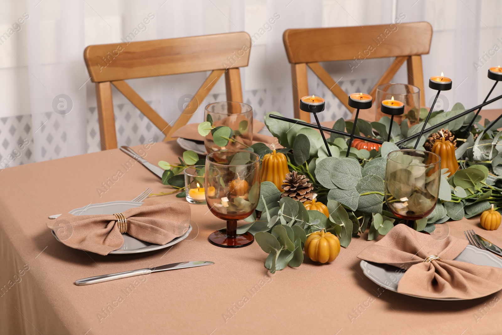 Photo of Autumn table setting with eucalyptus branches and pumpkins indoors