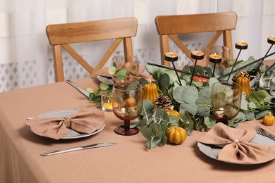 Photo of Autumn table setting with eucalyptus branches and pumpkins indoors