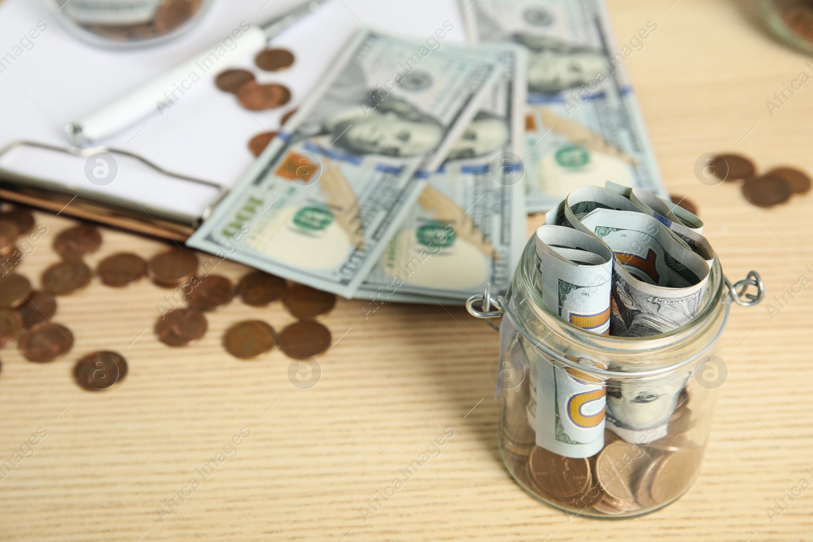 Photo of Glass jar with money on wooden table. Space for text