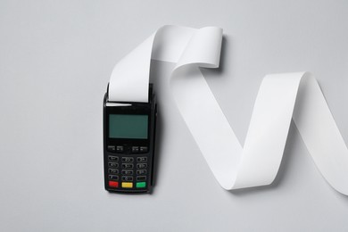 Payment terminal with thermal paper for receipt on light grey background, top view