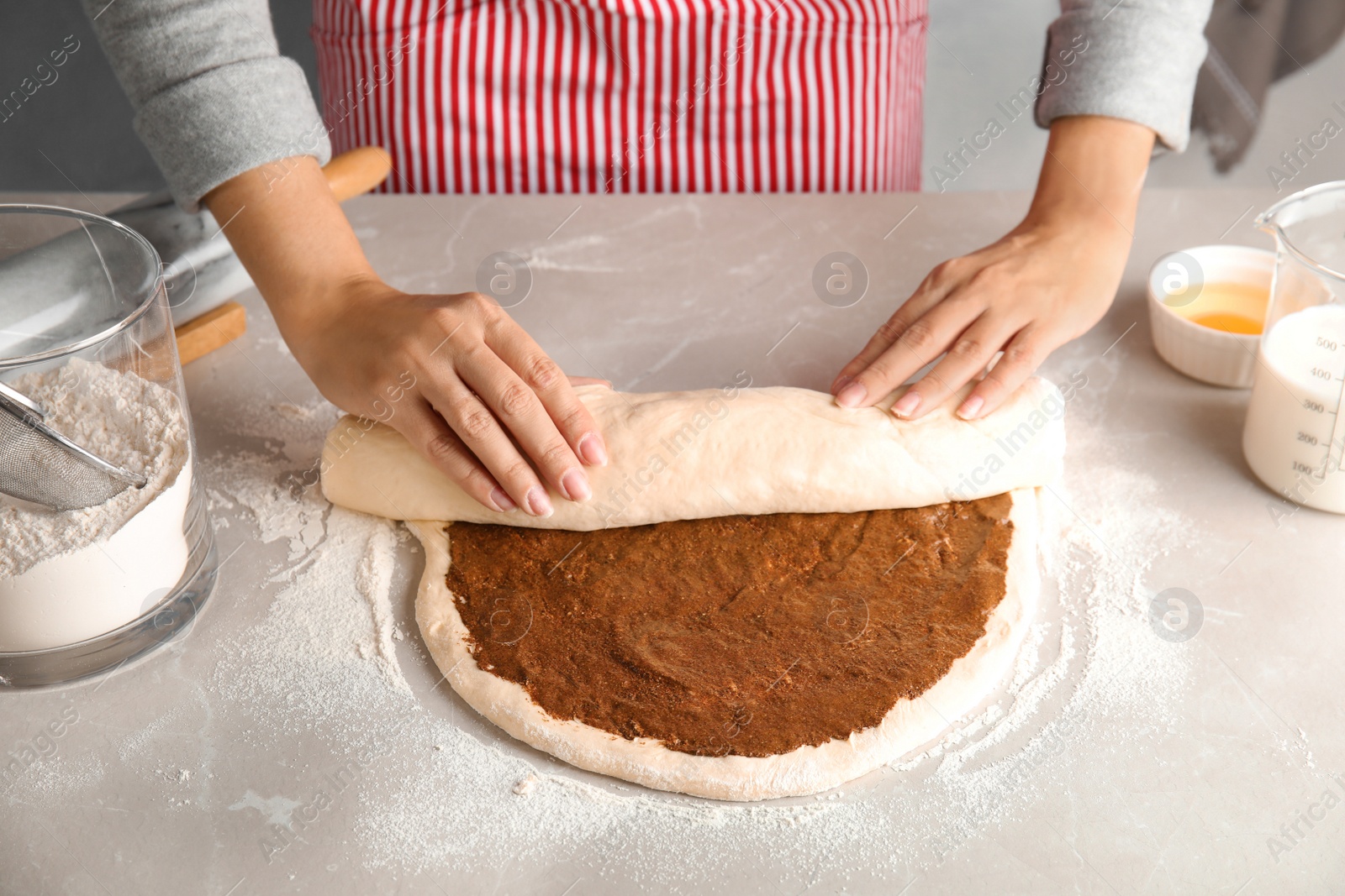 Photo of Woman making cinnamon rolls at table, closeup