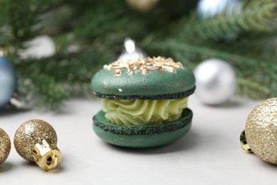 Photo of Decorated Christmas macaron and festive decor on white table, closeup