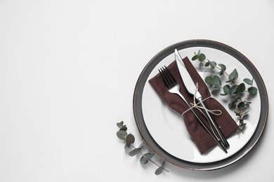 Photo of Stylish setting with cutlery and eucalyptus leaves on white background, top view. Space for text