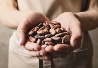 Photo of Woman holding pile of cocoa beans, closeup view