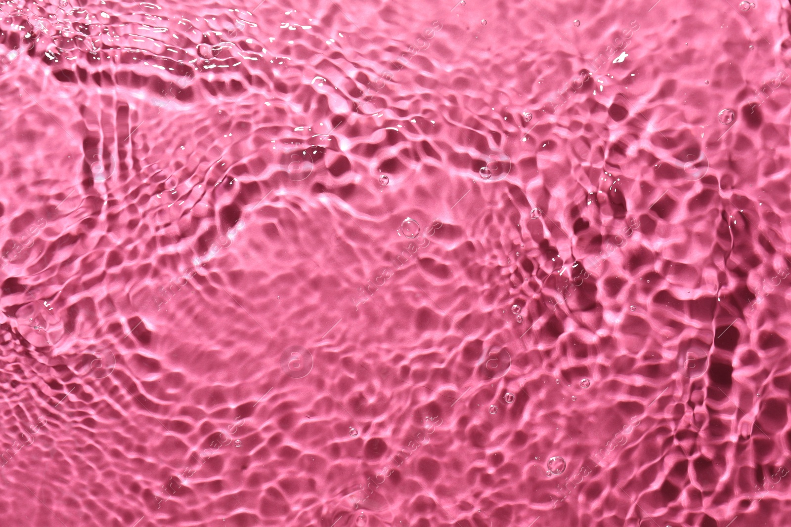 Photo of Rippled surface of clear water on bright pink background, top view