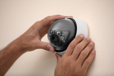 Photo of Technician installing CCTV camera on wall, closeup