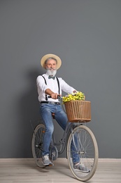 Portrait of handsome mature man with bicycle near color wall