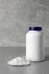 Photo of Jar and petri dish with calcium carbonate powder on grey table