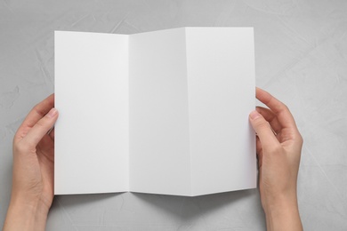 Photo of Woman with blank brochure on light background, above view. Mock up for design