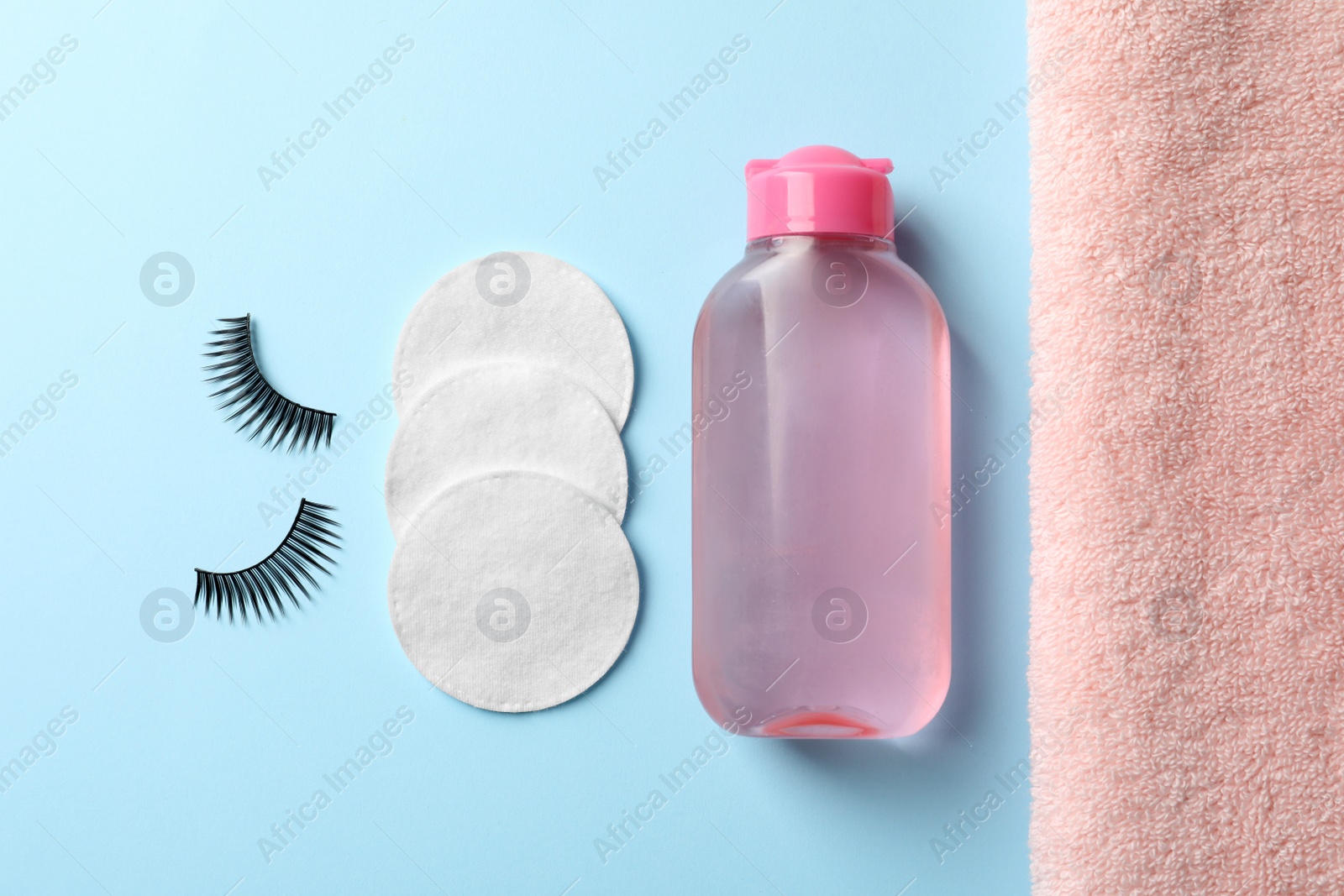 Photo of Flat lay composition with false eyelashes and makeup remover on light blue background
