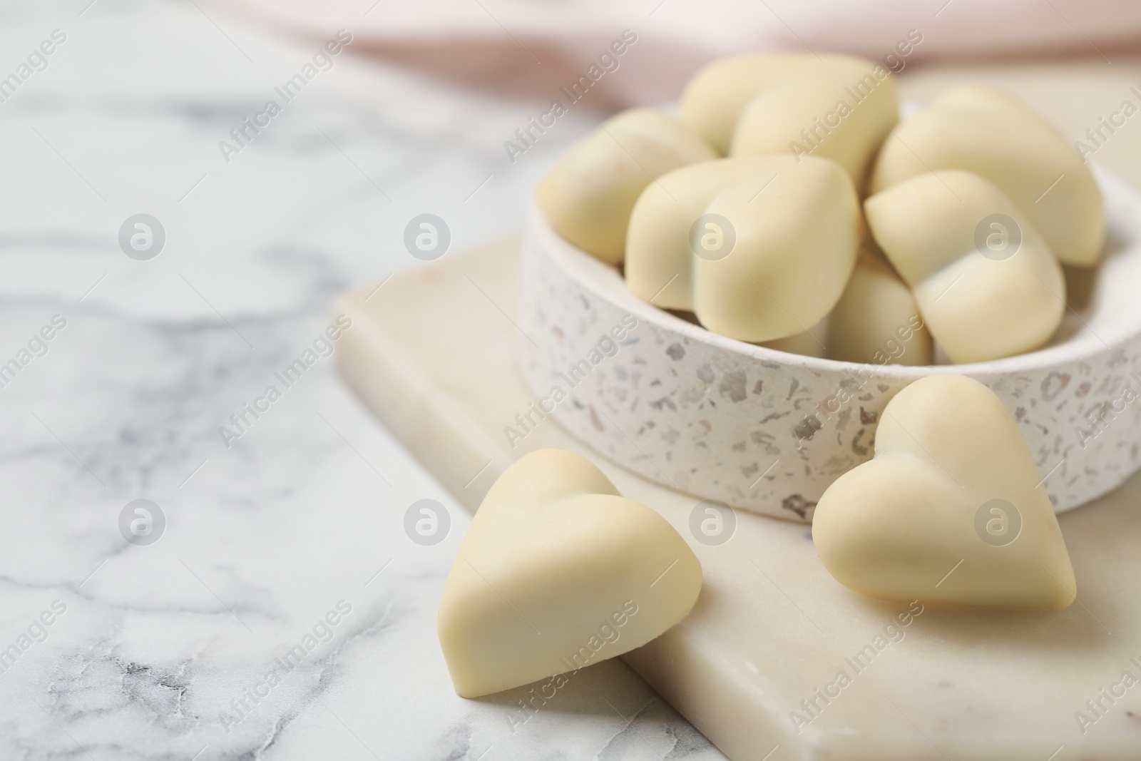 Photo of Beautiful heart shaped chocolate candies on white marble table, space for text