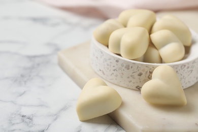 Beautiful heart shaped chocolate candies on white marble table, space for text