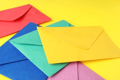 Colorful paper envelopes on yellow background, closeup