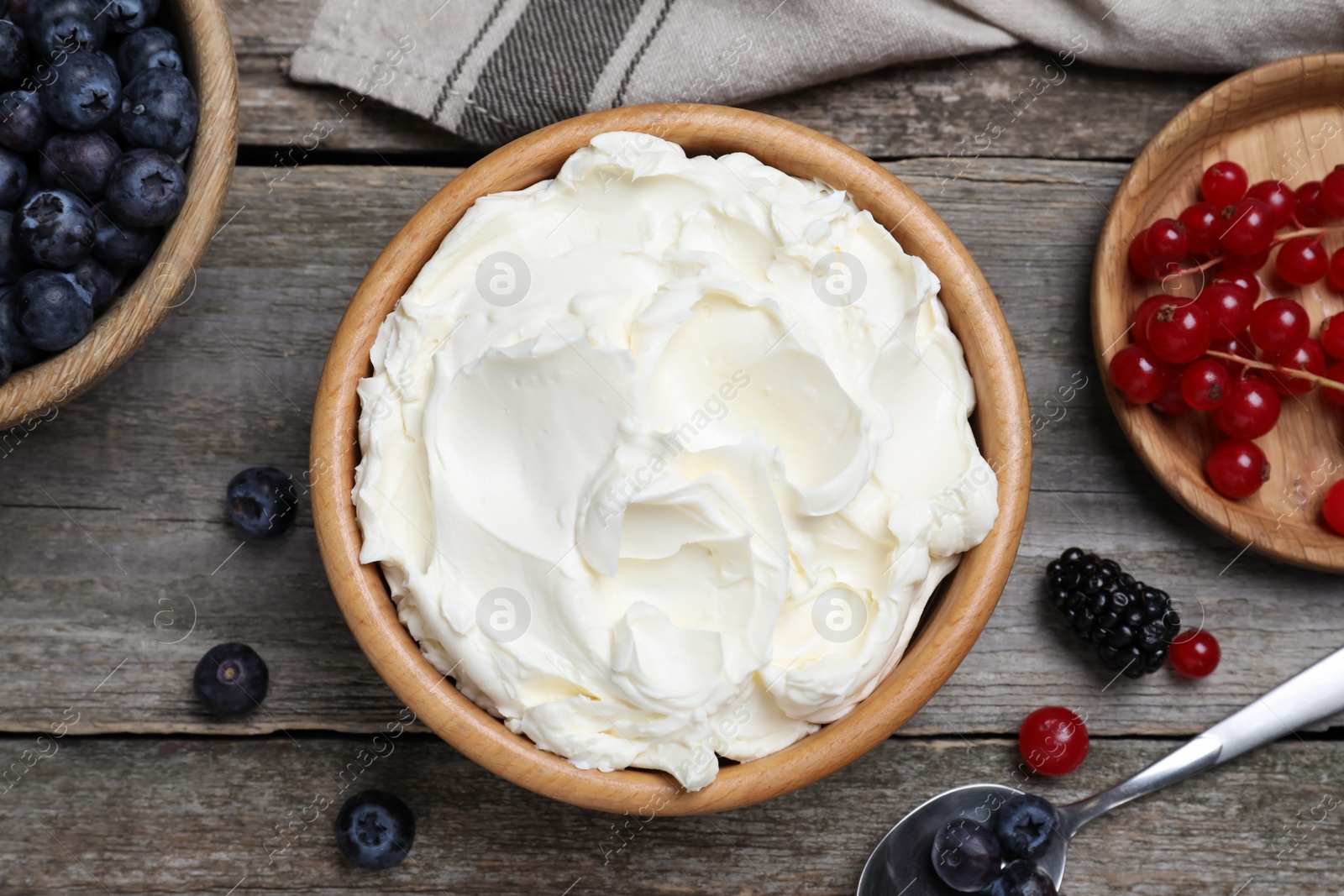 Photo of Tasty cream cheese and fresh berries on wooden table, flat lay