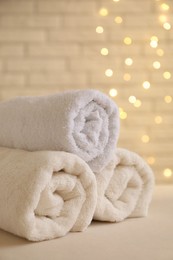 Photo of Rolled terry towels on white table near brick wall indoors