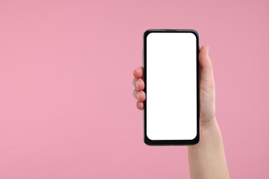 Photo of Woman holding smartphone with blank screen on pink background, closeup. Space for text