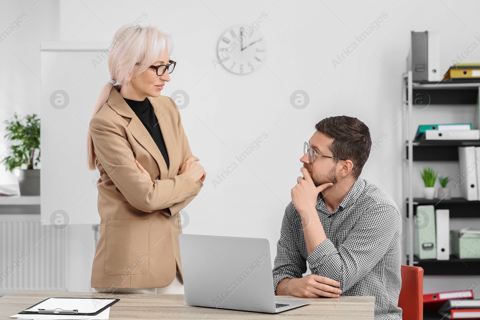 Photo of Boss and employee discussing work issues in office