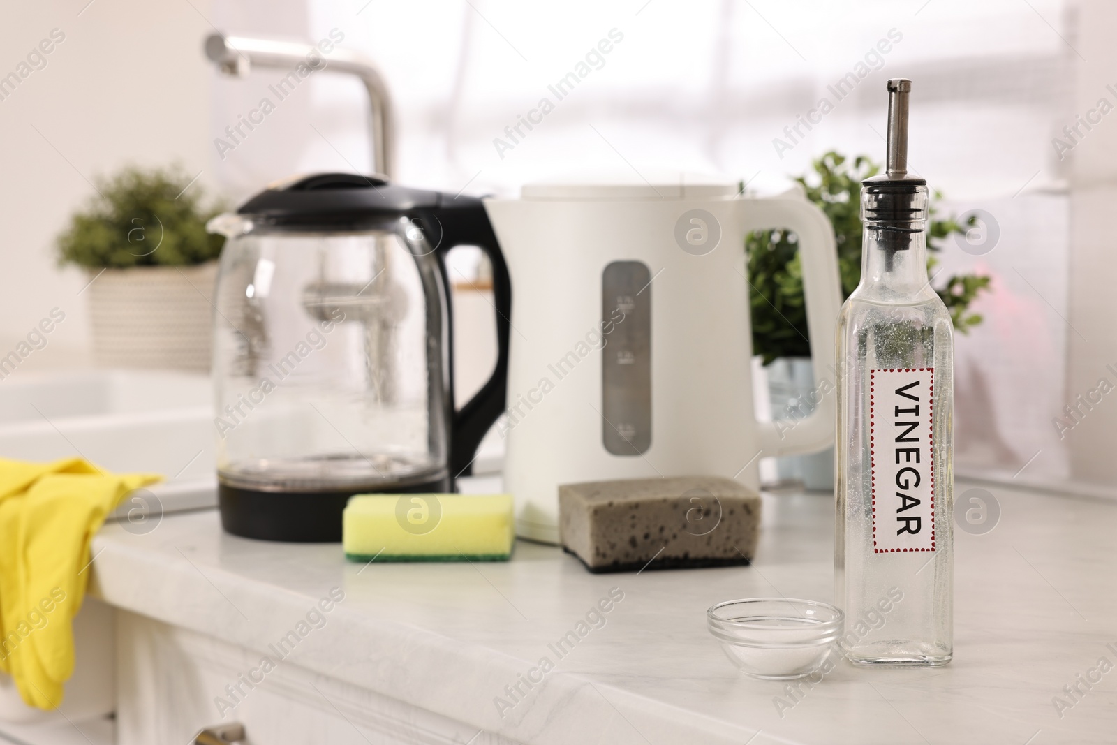 Photo of Cleaning electric kettle. Bottle of vinegar, sponges and baking soda on countertop in kitchen