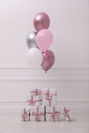 Many gift boxes and balloons near white wall in room