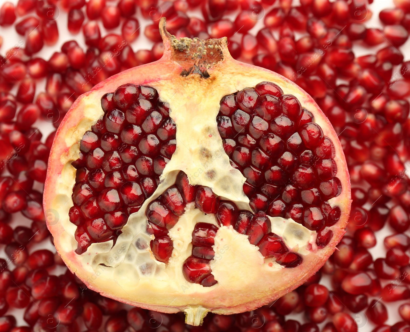 Photo of Ripe juicy red pomegranate on grains grains, top view