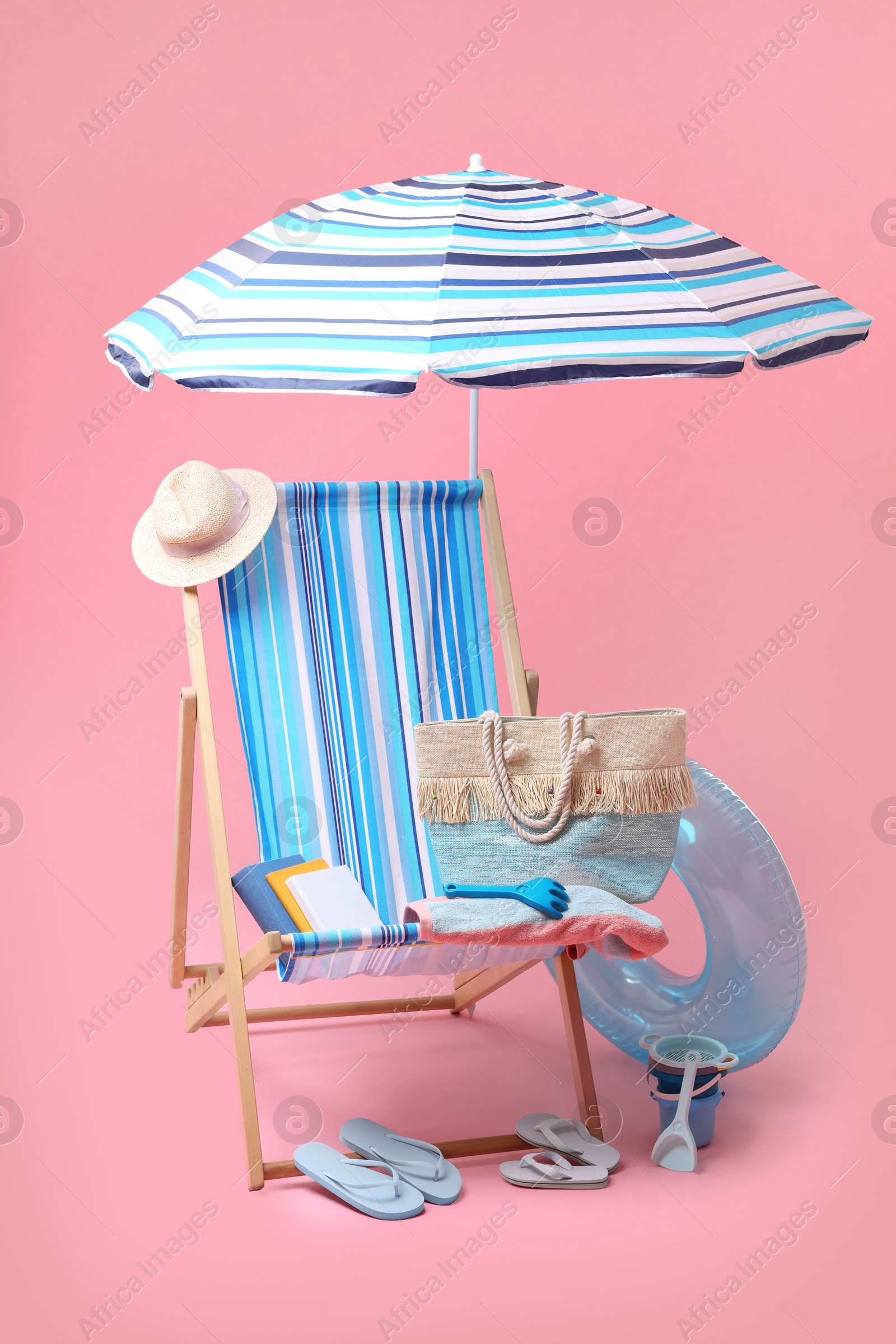Deck chair, umbrella and other beach accessories on pink background. Summer vacation Photo of Deck chair, umbrella and other beach accessories on pink background. Summer vacation