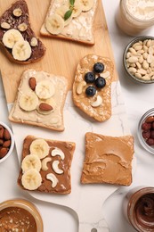 Photo of Toasts with different nut butters, fruits and nuts on white marble table, flat lay