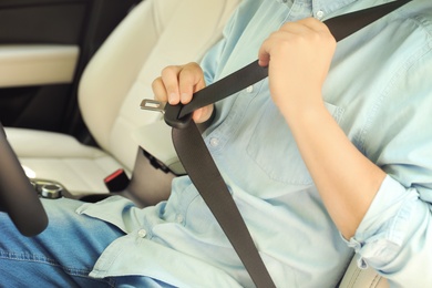 Photo of Male driver fastening safety belt in car, closeup