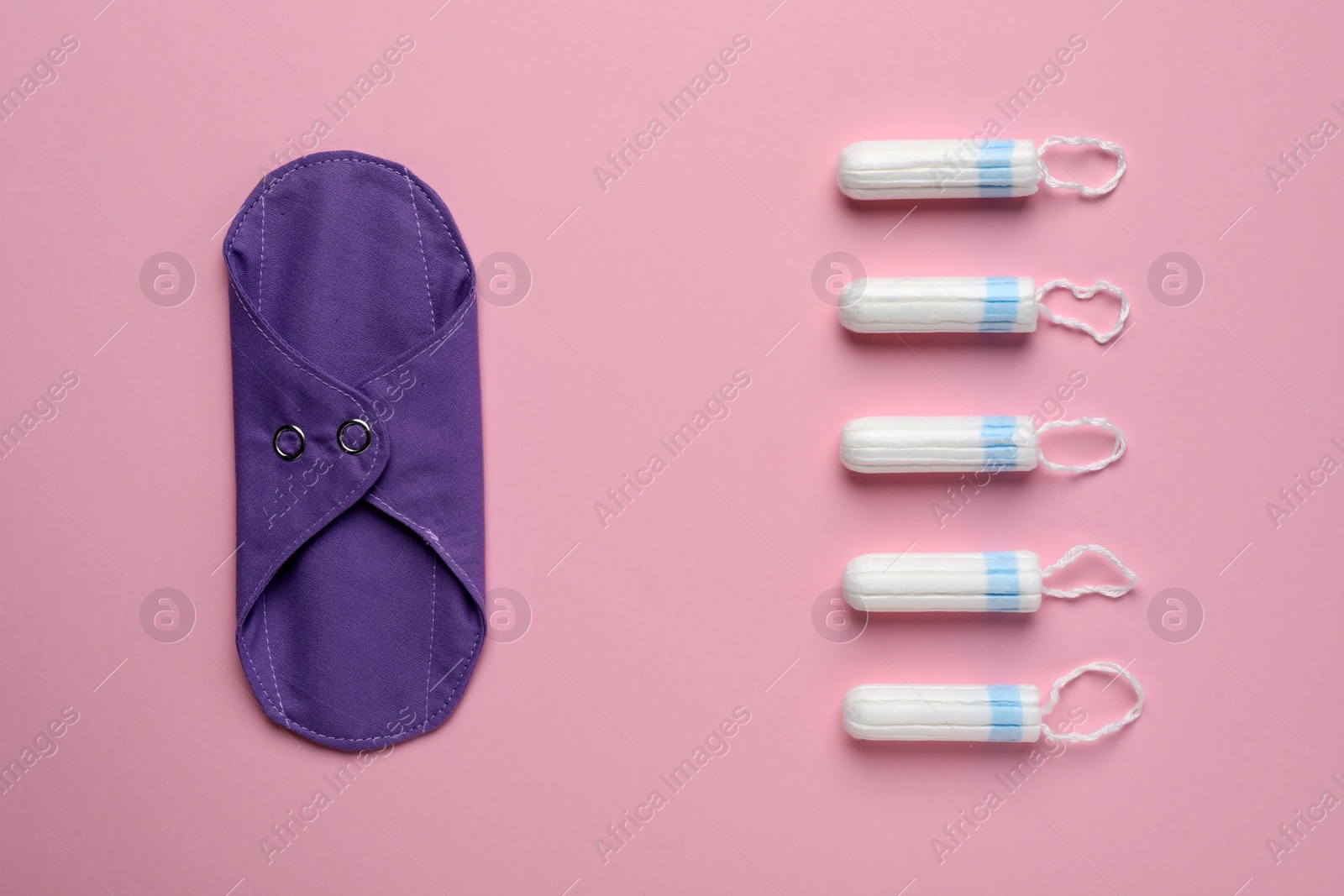 Photo of Reusable cloth menstrual pad and tampons on pink background, flat lay