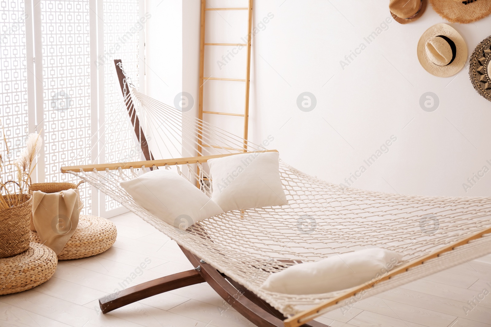 Photo of Comfortable hammock with pillows in stylish room. Interior design