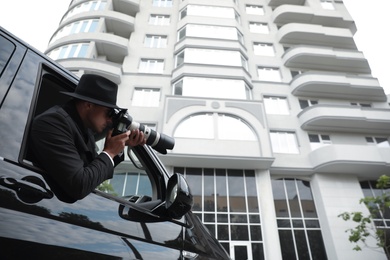 Private detective with camera spying from car, low angle view