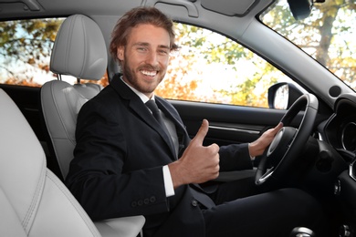 Happy handsome man in driver's seat of modern car