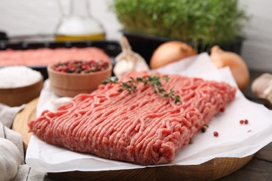 Photo of Fresh raw ground meat, thyme and peppercorns on table, closeup