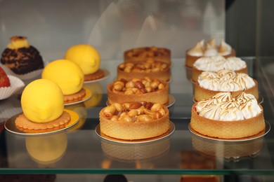 Photo of Showcase with different tasty desserts in store, closeup