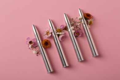 Photo of Metal bullets and beautiful flowers on pink background, flat lay