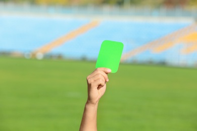 Photo of Football referee showing green card at stadium, closeup