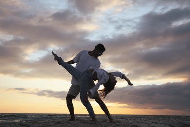 Happy couple dancing on beach at sunset