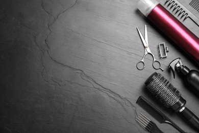 Photo of Flat lay composition of professional scissors and other hairdresser's equipment on black table, space for text. Haircut tool