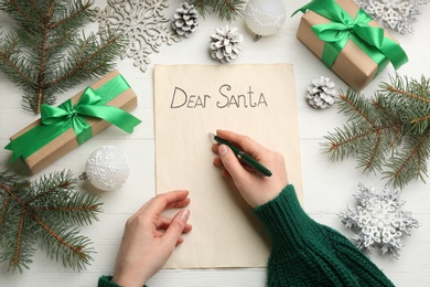 Top view of woman writing letter to Santa at white wooden table, closeup